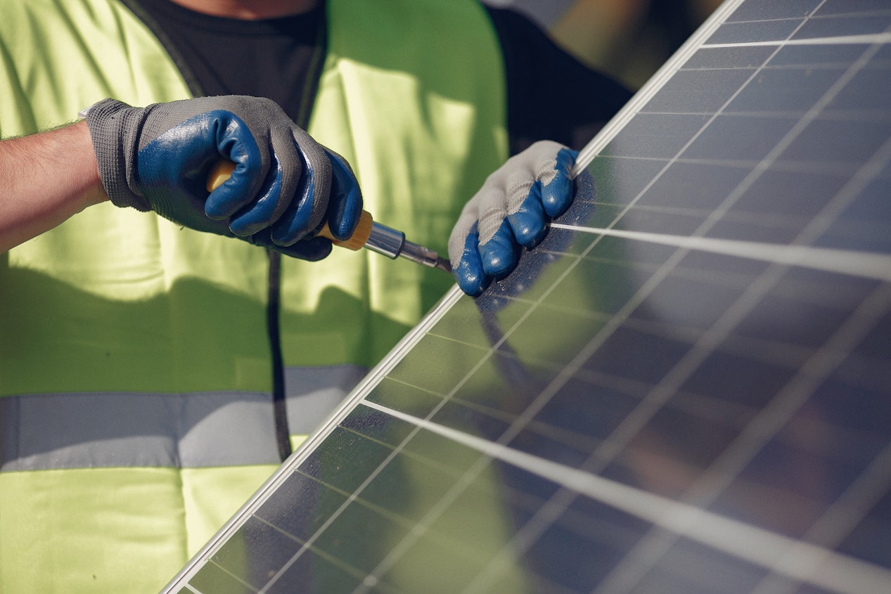 man-with-white-helmet-near-solar-panel