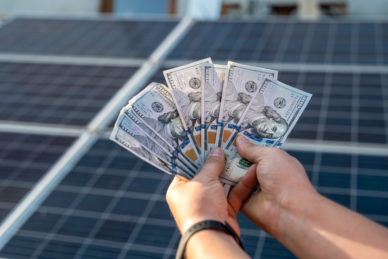 male-hand-hold-hundred-dollar-background-solar-station