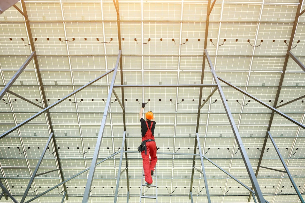 installing-wiring-solar-photo-voltaic-panel-worker-orange-uniform-connects-solar-panels-station